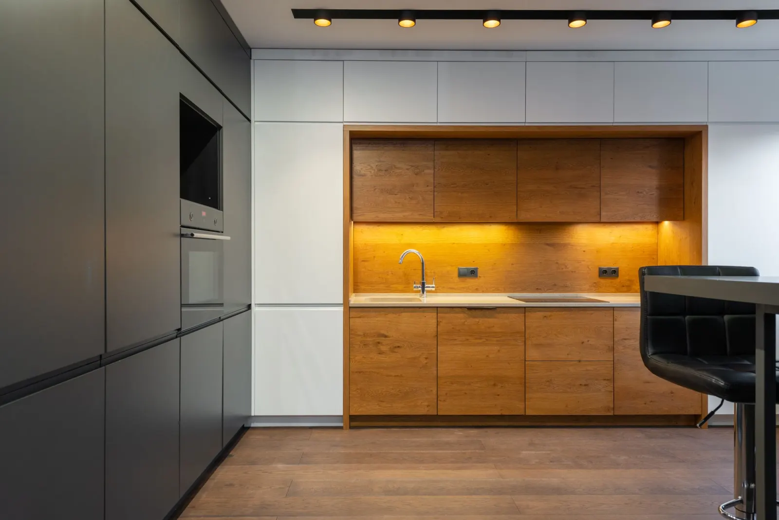 Ahşap detaylı, antrasit kapaklı modern mutfak dolapları ve bar tabureleri