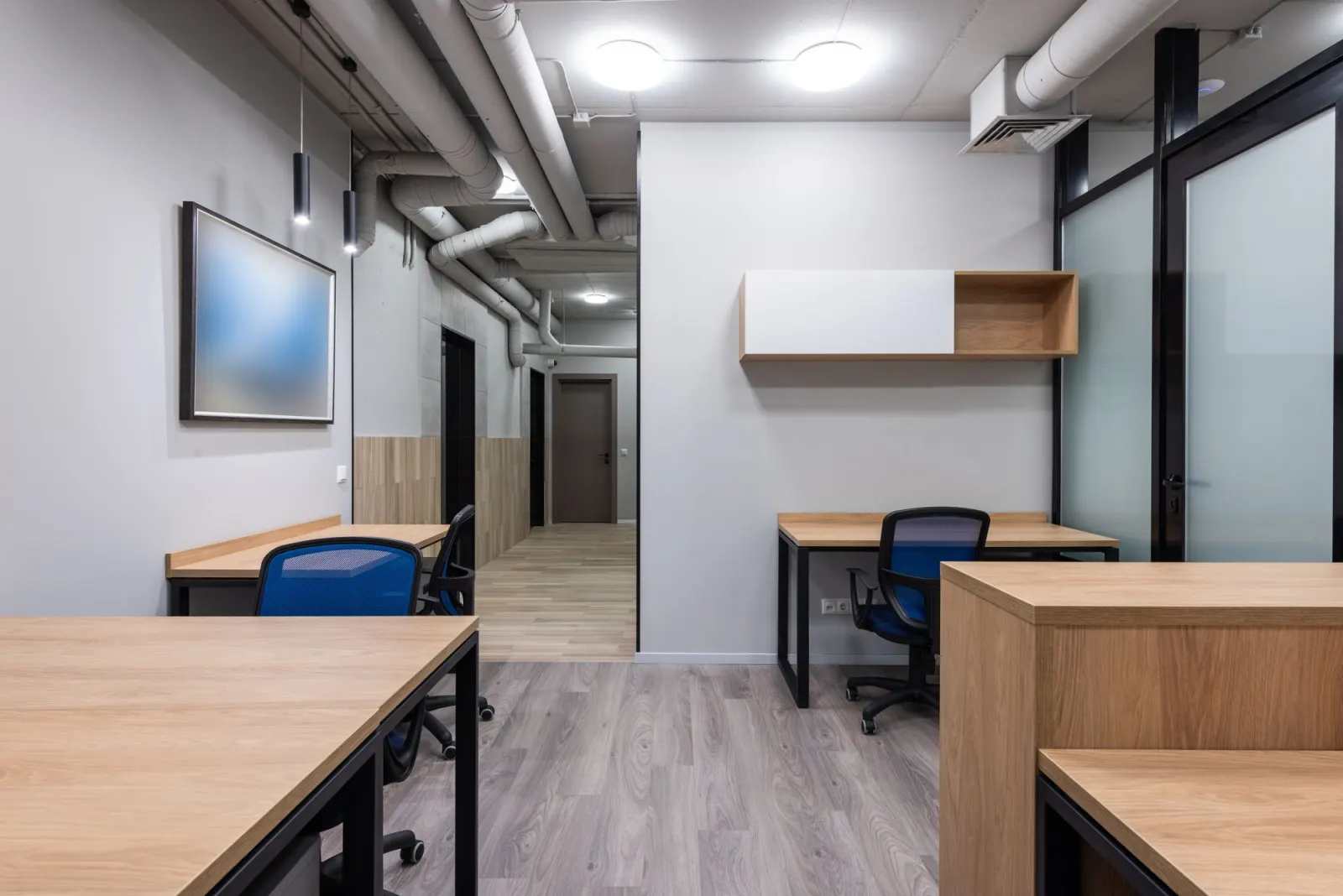 Ahşap masalar ve mavi sandalyelerle döşenmiş modern ofis