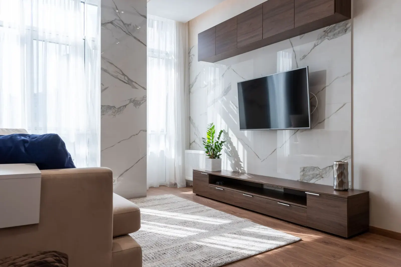 Mermer duvar önünde ahşap TV ünitesi ve duvara monte televizyon